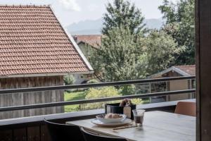 a table with a plate of food on a balcony at Chalets Lara & Louise in Rieden am Forggensee