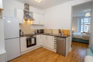 una cocina con armarios blancos y electrodomésticos de acero inoxidable en Vibrant City Centre - KING Bed, Entire Apartment en Cambridge