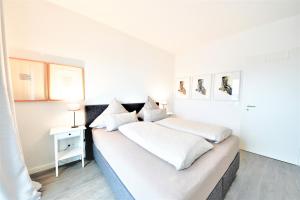 ein weißes Schlafzimmer mit 2 Betten und einer Lampe in der Unterkunft Seeblick Roter Sand in Wangerooge