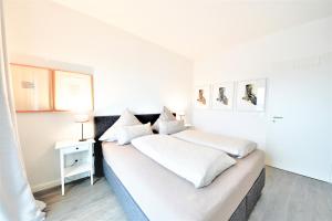 a white bedroom with two beds and a lamp at Seeblick Roter Sand in Wangerooge