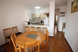 eine Küche und ein Esszimmer mit einem Holztisch und Stühlen in der Unterkunft Apart-rent Apartamento Gran reserva 0068 in Empuriabrava