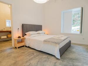 a white bedroom with a large bed and a window at Casa Som do Rio in Ponte de Lima