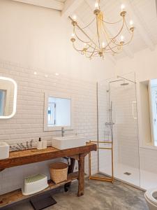 ein Badezimmer mit einem Waschbecken, einer Dusche und einem Kronleuchter in der Unterkunft Casa Som do Rio in Ponte de Lima