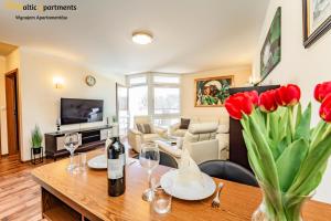 a living room with a table with wine glasses and red tulips at Baltic Apartments - Villa Mistral in Świnoujście