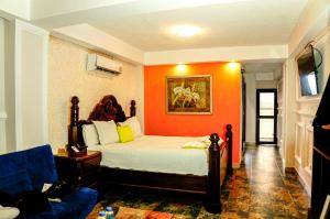 una camera con un letto con una parete arancione di Hotel Mi Paraíso Río Dulce a San Felipe