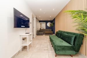 a living room with a green couch and a tv at Big House Next to Brighton Beach Sleep 16 I HENS PARTY & STAG DOS WELCOME in Brighton & Hove