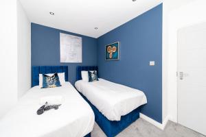 two beds in a room with blue walls at Big House Next to Brighton Beach Sleep 16 I HENS PARTY & STAG DOS WELCOME in Brighton & Hove