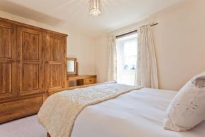 um quarto com uma cama com um armário de madeira e uma janela em No 6 The Forge Coniston em Coniston