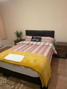 a bedroom with a bed with a yellow blanket on it at Lovely Shared 3 Bed Home Near The Thames in Thamesmead