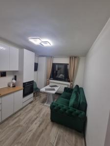 a living room with a green couch and a kitchen at UNIRII 107 in Constanţa