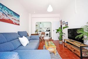 Una sala de estar con un sofá azul y un televisor. en Casa da Flor in Lagos, en Lagos