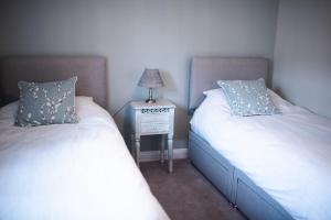 2 łóżka pojedyncze w pokoju z szafką nocną w obiekcie Howgill House Barn w mieście Draughton