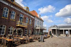 un patio con tavoli e sedie di fronte a un edificio di BnB onder de Blauwe Hemel a Vlijmen