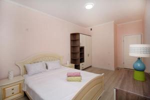 um quarto com uma grande cama branca e um candeeiro em ЖК Верный, 3-комнатная квартира, рядом с верхней Мегой, вдоль речки em Almaty