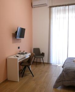 - une chambre avec un bureau, un lit et une télévision dans l'établissement Palazzo Ferrara 1952, à Naples