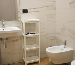 La salle de bains blanche est pourvue d'un lavabo et de toilettes. dans l'établissement Palazzo Ferrara 1952, à Naples