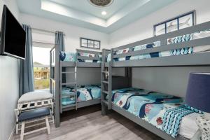2 Etagenbetten in einem Zimmer mit einem TV in der Unterkunft Gulf Front - Mini Golf - Hot Tub - Family Friendly - ForeShore in Bolivar Peninsula