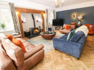 a living room with leather furniture and a fireplace at Pengwern in Llanrwst