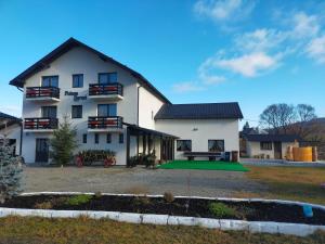 a large white house with a green lawn in front at Pensiunea Poiana Dornei in Vatra Dornei