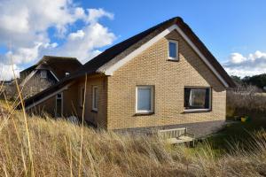 ein kleines Backsteinhaus auf einem Feld mit hoher Wiese in der Unterkunft in het Dal in Buren