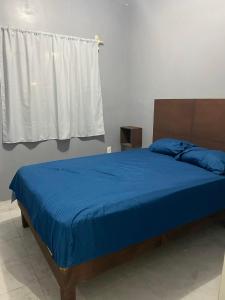 una camera da letto con un letto con lenzuola blu e una finestra di Departamento Altamira Puerto Industrial ad Altamira