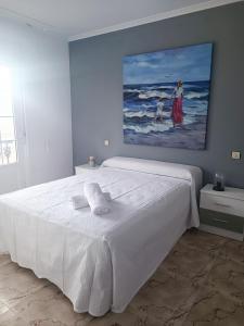 1 dormitorio con 1 cama blanca y una pintura en la pared en Casa El Rincón de Alberto con Calefacción y piscina, en Camelle