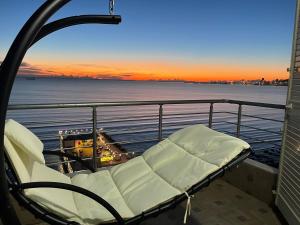 a balcony with a chair on a ship with a sunset at LuxurySeaview Apartment in Durrës