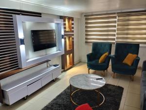 a living room with a tv and two chairs and a table at Rgr ONE BEDROOM APARTMENTS in Lagos