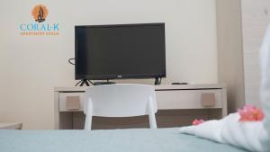een televisie op een bureau met een witte stoel bij CoralK Apartments Sosúa in Sosúa
