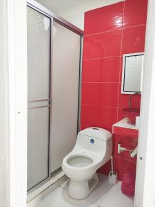 a bathroom with a toilet and a red wall at Apartamentos Villa Leonor in Coveñas