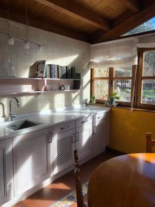 eine Küche mit weißen Schränken, einer Spüle und einem Tisch in der Unterkunft Casa Laudina y Armando in Brañella