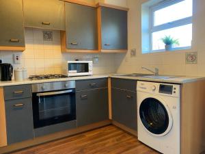 a kitchen with a washing machine and a microwave at House - 10min to City Centre - Sleeps 4 - Parking in Birmingham