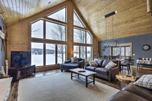 sala de estar con sofás, TV y ventanas en Lakefront Cottage in Iron River with 2 Porches!, en Iron River