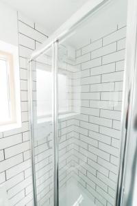 a glass shower in a white bathroom with a window at Delores Eco-Pod / Treehouse, Walk to Cabot Circus in Bristol