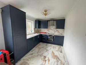 a kitchen with blue cabinets and a marble floor at Modern 2 bedroom flat by Dover Port, Castle& Sea! in Kent