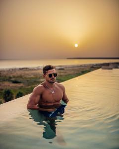 a man in the water at the beach at sunset at Zahara Beach & Spa by QHotels - Adults Recommended in Zahara de los Atunes