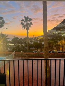 a view of a sunset from a balcony with palm trees at Mar Paraiso in Playa del Cura