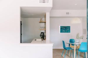 a kitchen and dining room with blue chairs and a table at Unit 124 - The Strand 2 Bed - Cation on the Guadalupe in New Braunfels