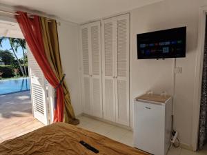 - une chambre avec un lit et une télévision murale dans l'établissement Appartements de Luxe . Propriété de Luxe, à Baie-Mahault