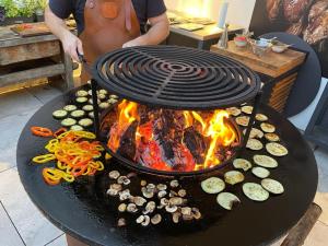 un hombre cocinando comida en una parrilla con fuego en Biohofgut LASCHALT, en Deutsch Kaltenbrunn