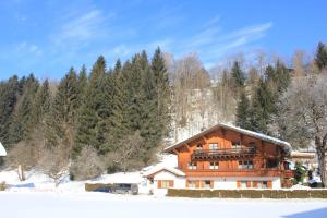 a large wooden house in the snow with trees at Utas Ferienhof in Sankt Gallenkirch
