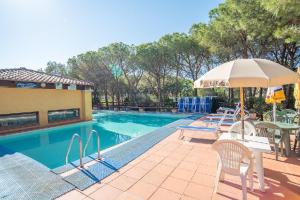 a pool with tables and chairs and an umbrella at La Casa delle Conchiglie in Capo Coda Cavallo