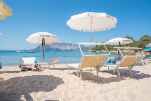 a group of chairs and umbrellas on a beach at La Casa delle Conchiglie in Capo Coda Cavallo
