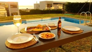a table with a plate of food and a bottle of wine at Modern 4 Double Bedroom Villa with Pool / Garden in Valdoviño