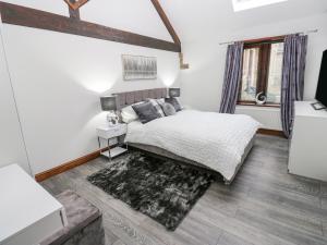 a white bedroom with a bed and a rug at Dale Cottage in Oldham