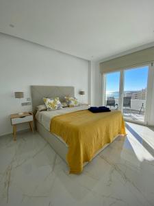 Apartamento Ronda III في فوينخيرولا: غرفة نوم بيضاء مع سرير وبطانية صفراء