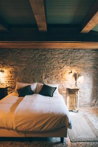 1 dormitorio con cama y pared de piedra en Casa immersa nelle colline romagnole, en Civorio