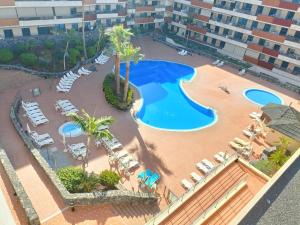 een uitzicht over een zwembad met stoelen en palmbomen bij Luxury Los Gigantes Apartment in Puerto de Santiago