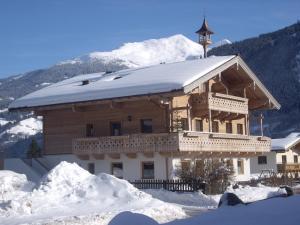 une grande maison en bois avec un toit enneigé dans l'établissement Ferienwohnungen am Biobauernhof Lahner, à Bramberg am Wildkogel