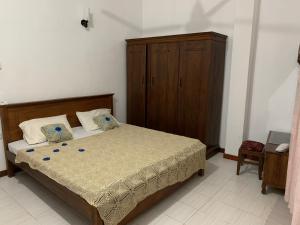 1 dormitorio con 1 cama y armario de madera en Little Apartment, en Galle